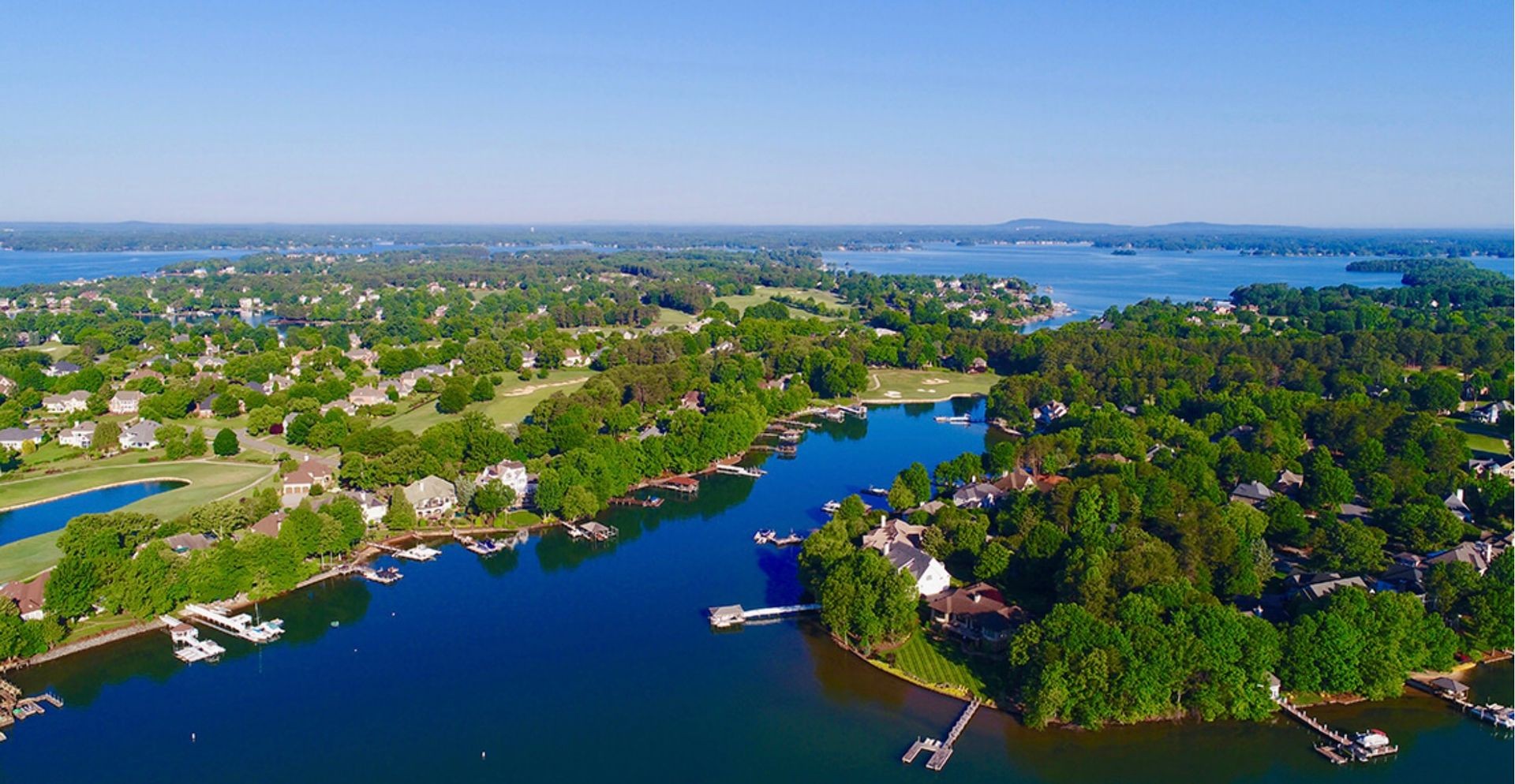 Aerial view of a suburban lakeside community with greenery and residential houses.